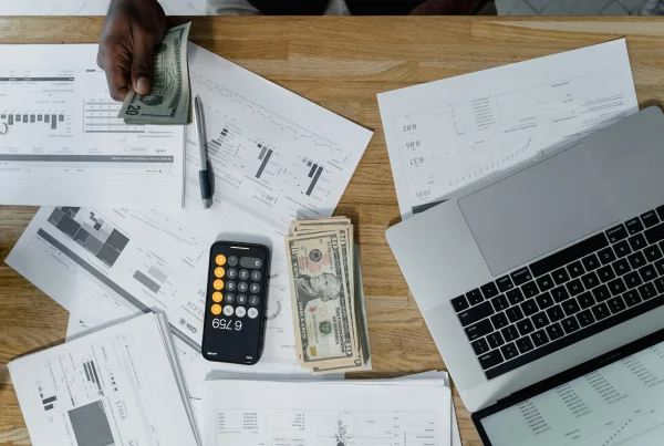 Professional workspace with laptop showing global payroll system and currency transactions