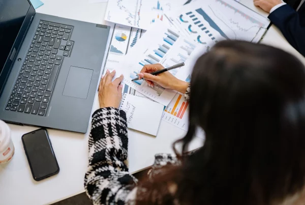 HR professional managing distributed workforce payroll on a laptop while reviewing employee documents and payroll records