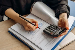 Un professionnel de la finance examinant des documents fiscaux, calculant les montants de la paie et veillant à l'exactitude de la paie à l'échelle mondiale sur un ordinateur