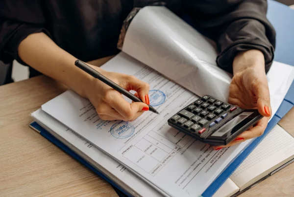 Finance professional reviewing tax documents, calculating payroll figures, and ensuring global payroll accuracy on a computer