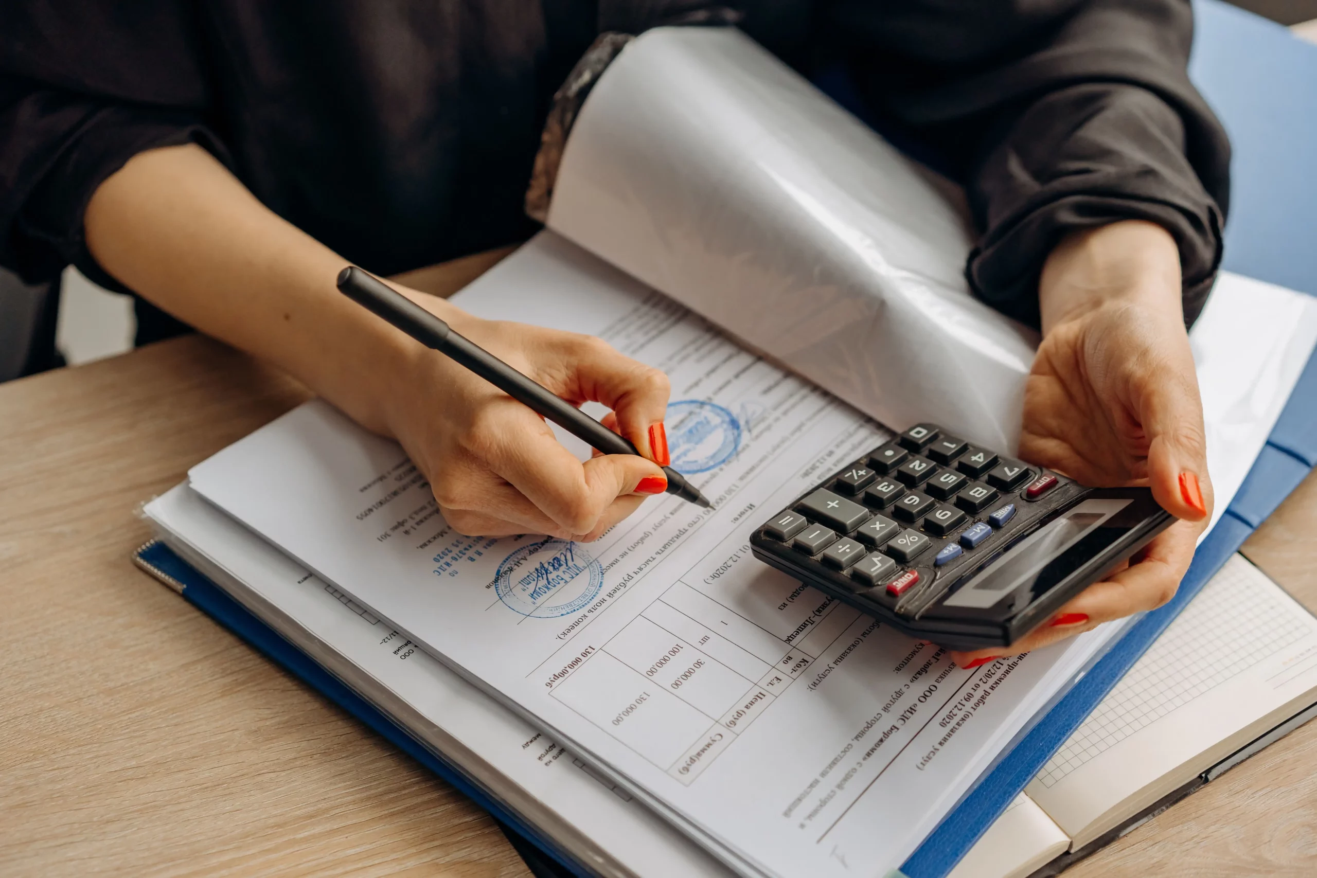 Finance professional reviewing tax documents, calculating payroll figures, and ensuring global payroll accuracy on a computer