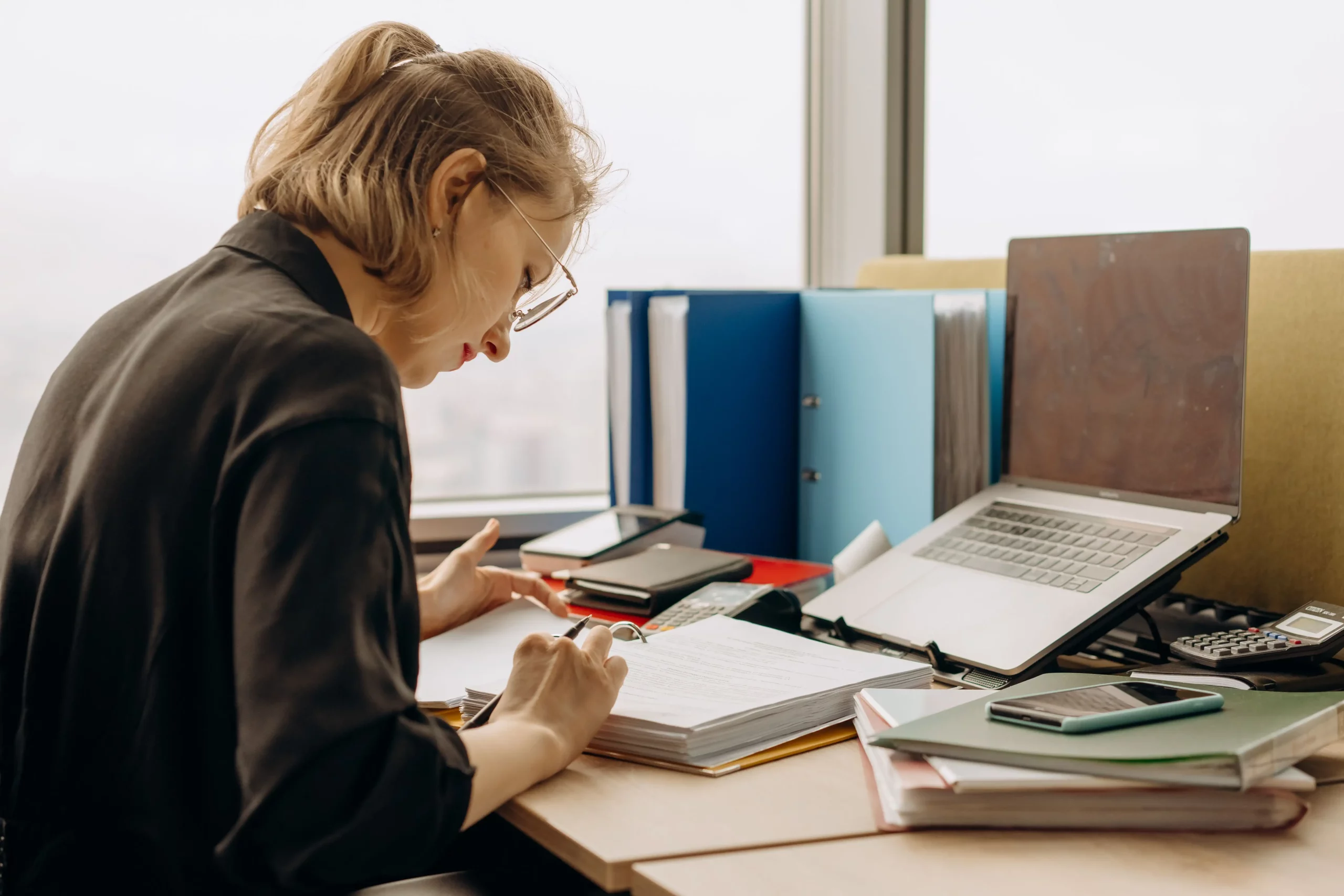 A professional working on a laptop while using payroll filing software to manage employee payroll, tax filing, and business records in a modern office.
