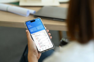 Une femme utilise le logiciel de suivi des horaires et des absences Applic8 sur son smartphone pour vérifier ses heures de travail, soumettre des demandes de congé et gérer ses présences.